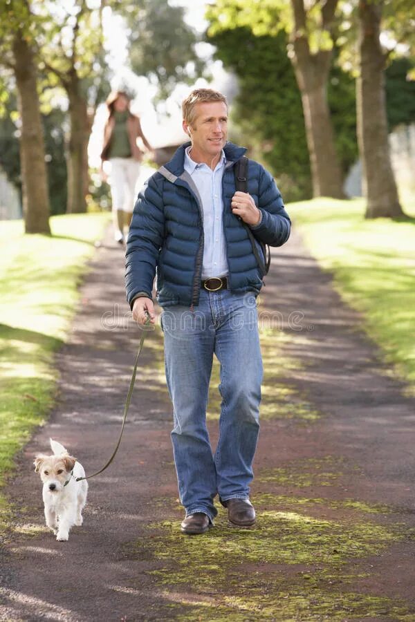 Телефон погулять. Мужчина гуляет с собакой в парке. Прогулка с собакой. Люди гуляют в парке. Прогулка с собакой в парке.