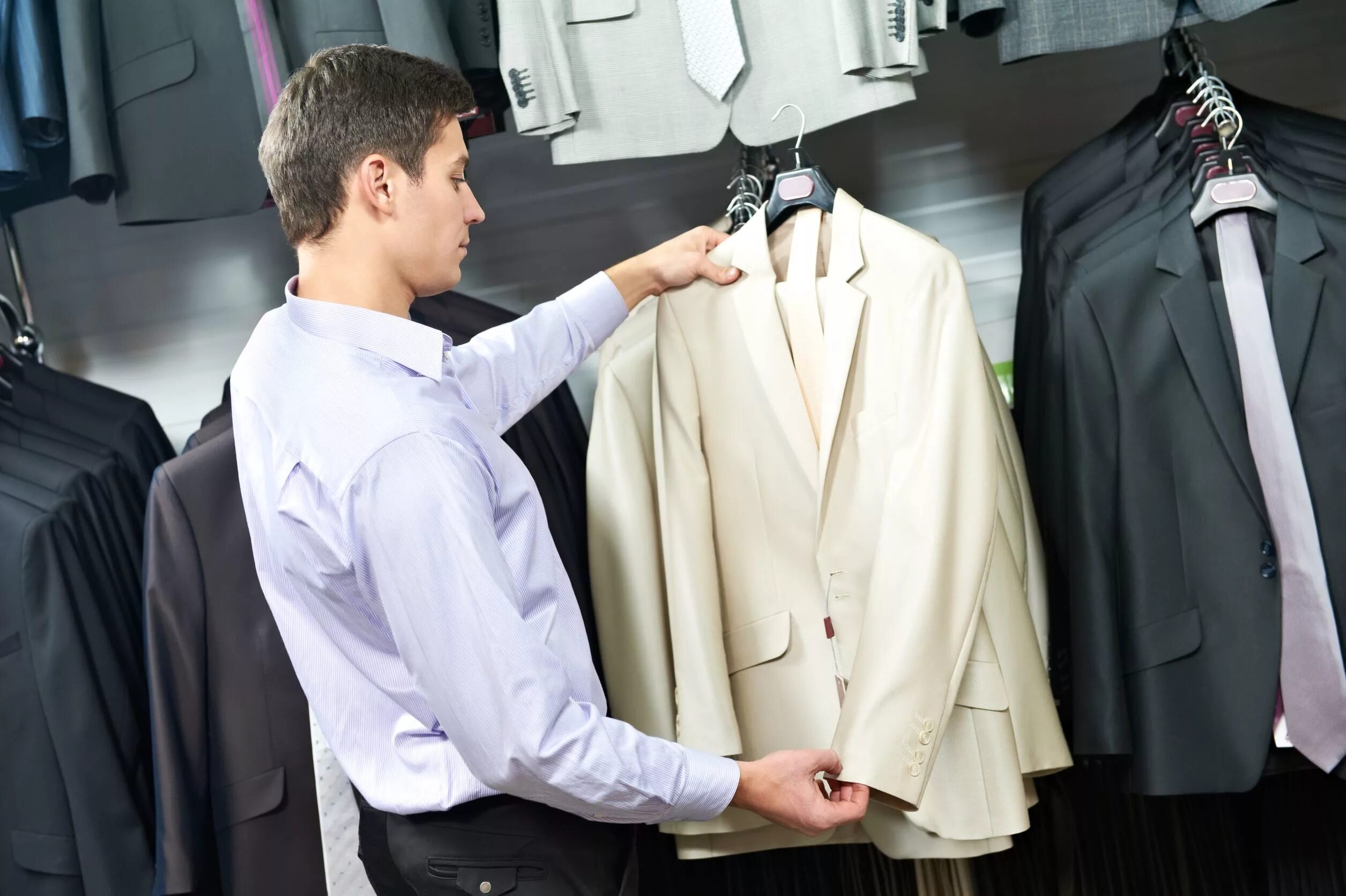 Вещи выбирают хозяина. Примерка одежды. Мужчина примеряет костюм. Примерка одежды в магазине. Бутик мужских костюмов.