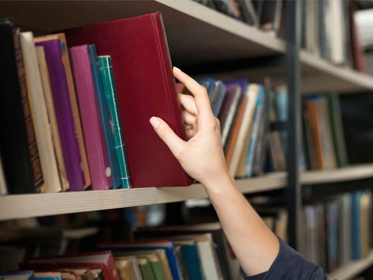 Мужчина в библиотеке. Книга достала с полки. Достает книгу с полки. Фотосессия в библиотеке. Книга достала с полки.