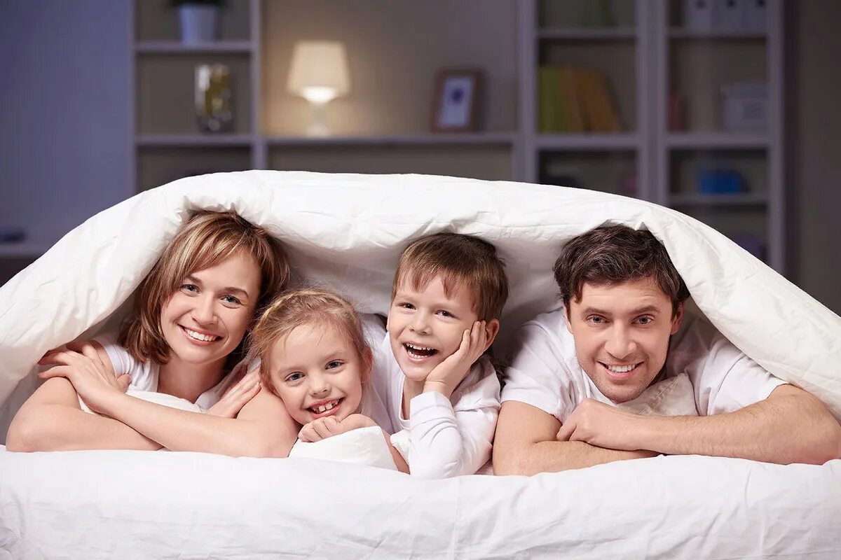 Семейная фотосессия. Семьи с детьми в гостинице. Семья на кровати. Счастливая семья в постели.