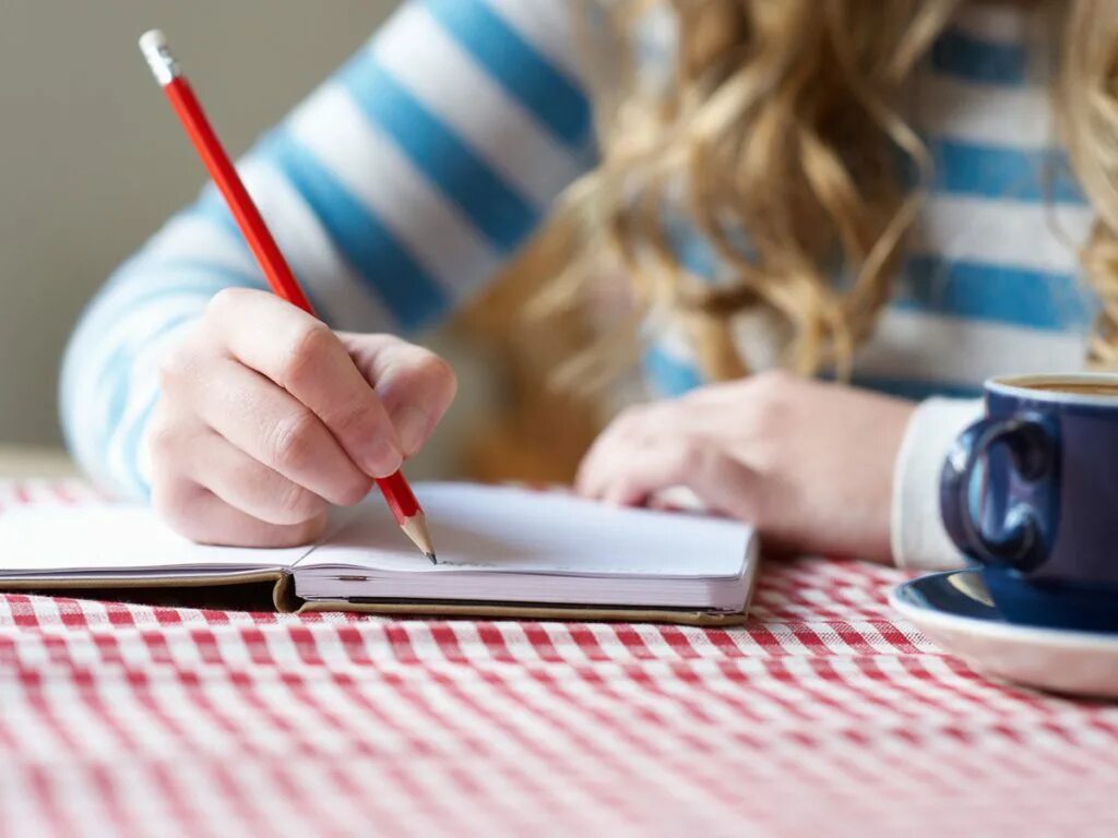 Человек пишет. Блокнот для записей. Девушка пишет список дел. Фон ноутбук на столе с блокнотом. 100 желаний.