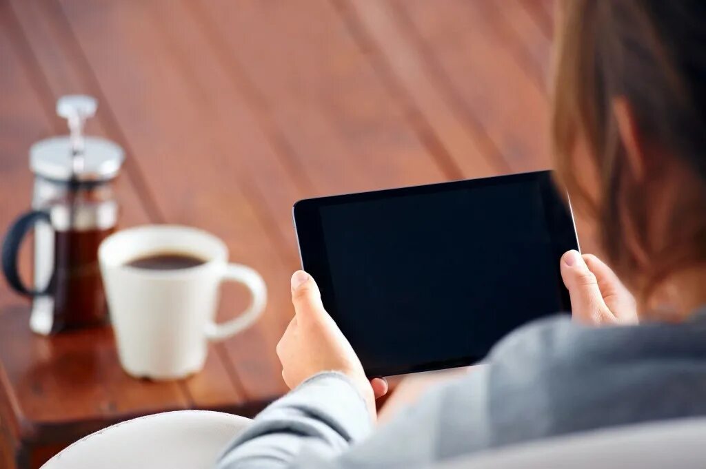 Relaxed ordering. Looking at tablet. young woman relaxed at heater with tablet in hand. a beautiful woman drinking coffee on the sofa.