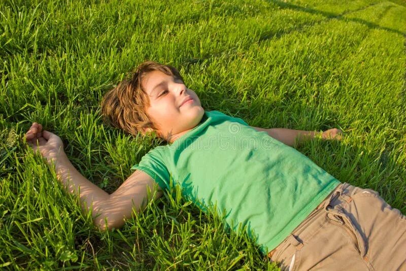 Мальчик лежит на траве. Мальчик лежит. Мальчик валяется на траве. Мальчик лежит на лужайке.