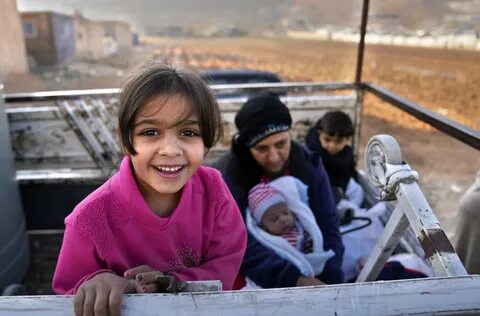Hundreds of Syrian refugees boarded a convoy of trucks laden with mattresse...