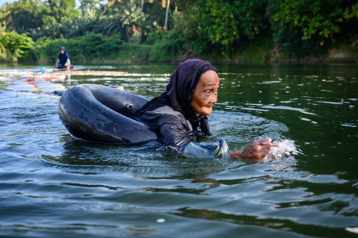 Остров Сулавеси Индонезия. Бабушка с водой. Бабка плавает в реке. Пресная вода на острове