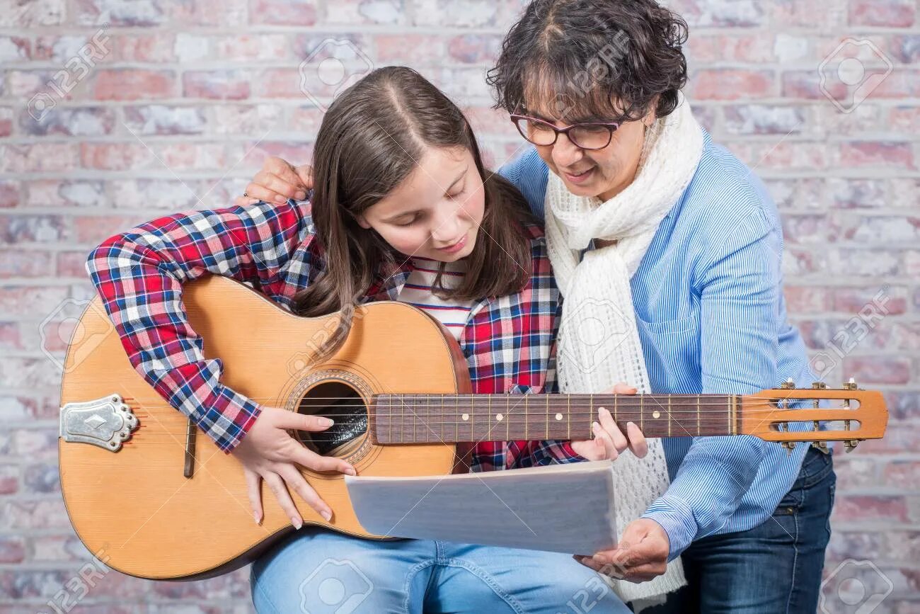 Подросток играет на гитаре. Игра на гитаре подросток. Человек обучает игре на гитаре. Парень учит играть на гитаре. Играть на гитаре молодая