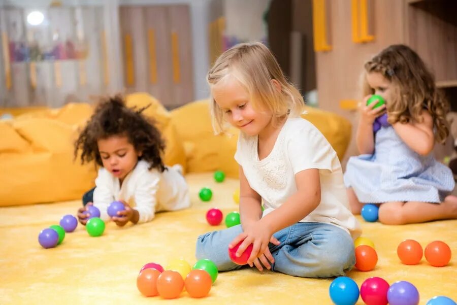 Learning through play. Children play with toys. child playing with toys. воспитатель в кругу играет с детьми в мяч.