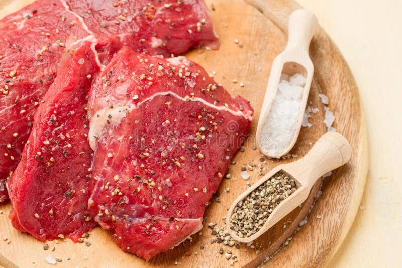 Стейк говядина на сковороде. Нарезка мяса на порционные куски. Лангет из говядины полуфабрикат. Мясо на деревянной доске. Отбивают ли говядину.