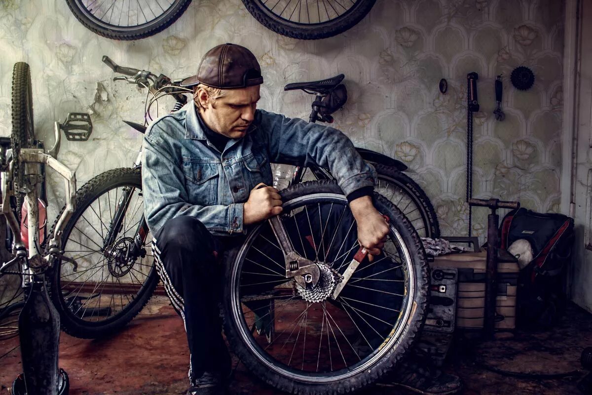 Где ремонтируют велосипеды. Чинит велосипед. Человек чинит велосипед. Мужчина чинит велосипед. Веломастерская.