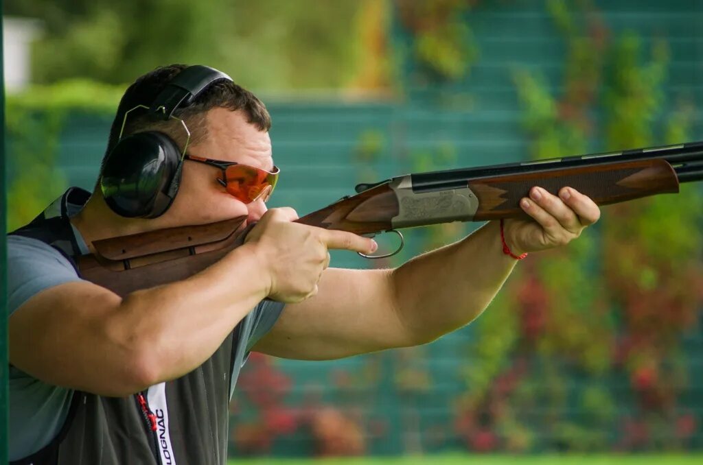 охотник стреляет. стрельбище для охотников. огонь из пистолета. стрельба из ружья. охотник с оптическим прицелом.