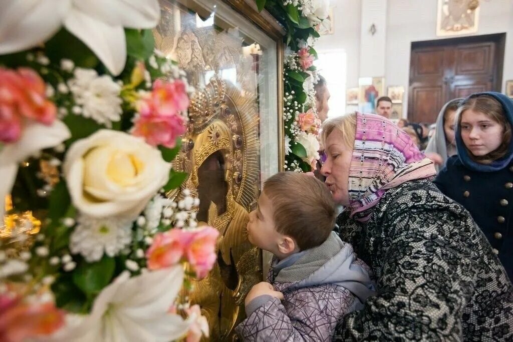 Девушка у иконы в храме. Целование икон в церкви. Как прикладываться к мощам святых в храме. Приложиться к иконе. Люди в храме.