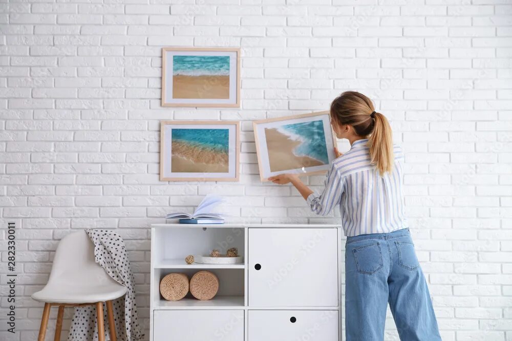 Штанга для развески картин. Hang picture. Hang picture. Девушка вешает картину на стену. Развеска картин в музее.