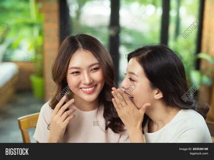 Two Asian Women Friends Chatting And Gossipping.