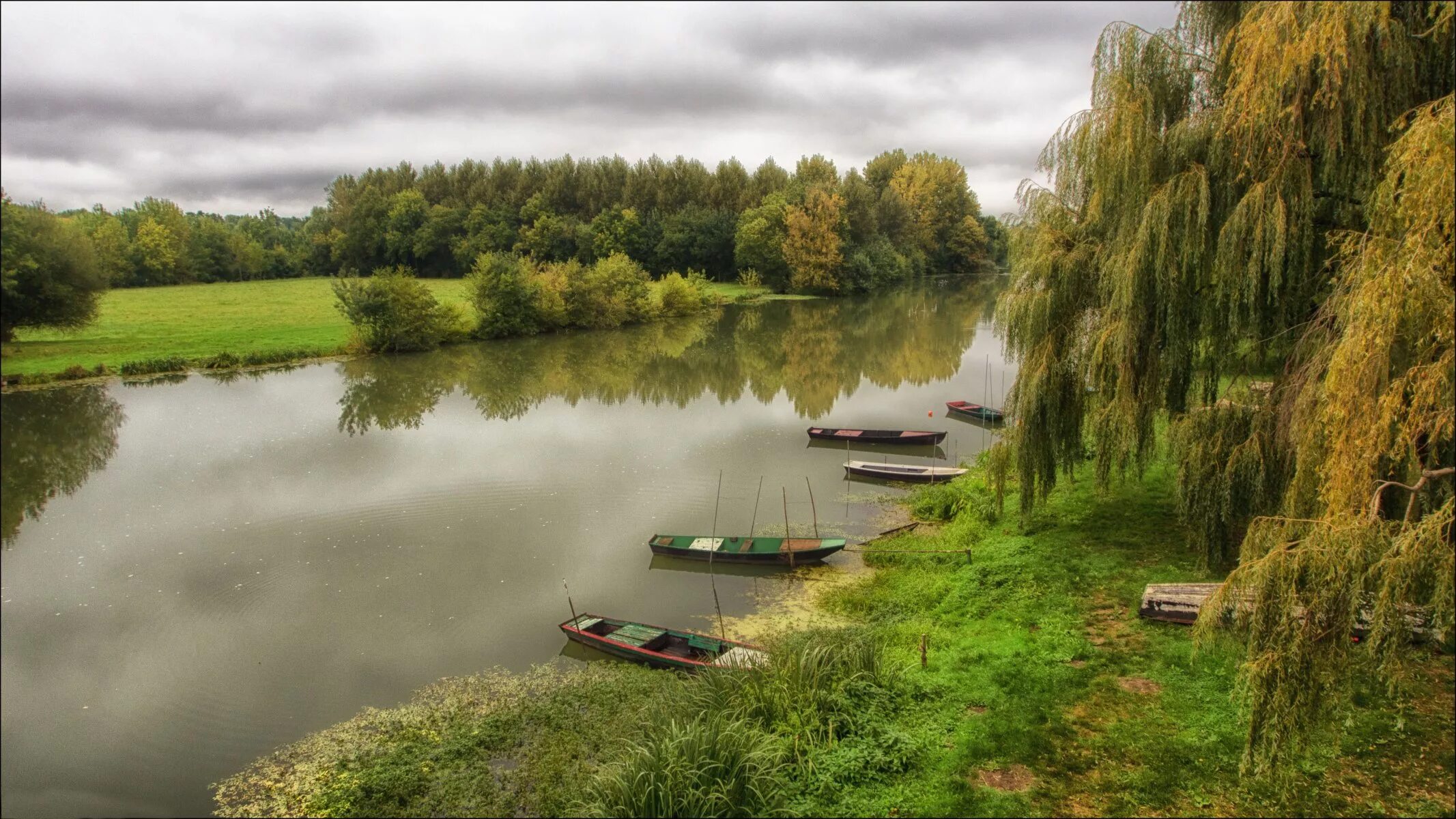 Рыбак на берегу водоема. Река Вышний Пенская деревушка. Пейзаж. Речной пейзаж. Берег реки.