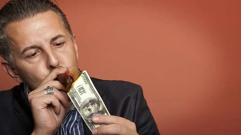 Богатый бизнесмен. Бизнесмен с сигарой. Богатый человек с сигарой. Бизнесмен закуривает деньгами.