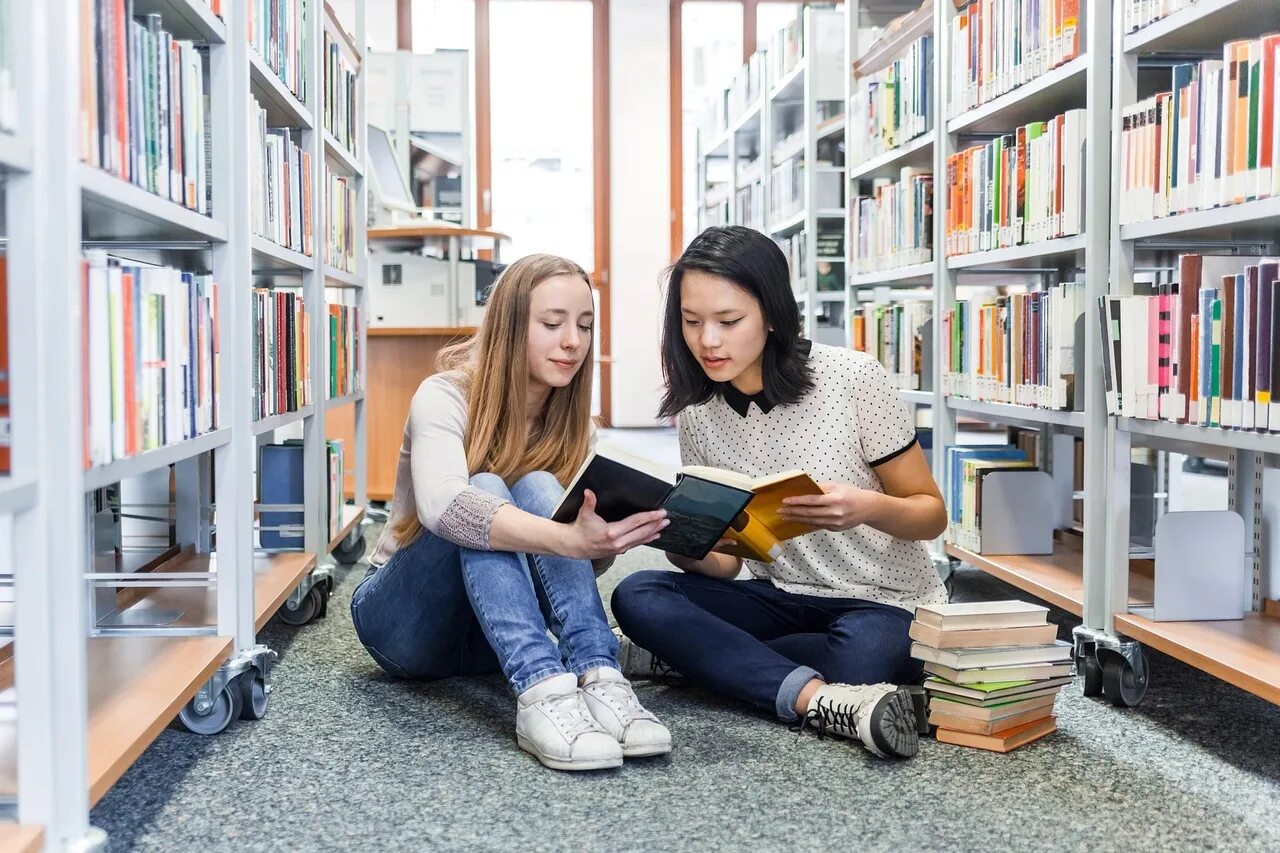 She often reads books. Подростки в библиотеке. Девушка в библиотеке. Две девушки в библиотеке. Студенты в библиотеке.