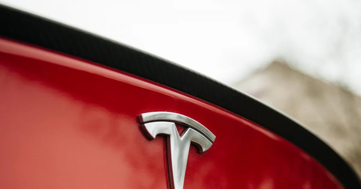 Знак красный автомобиль. Tesla шильдик. Тесла знак. Тесла машина логотип. Тесла знак на машине.