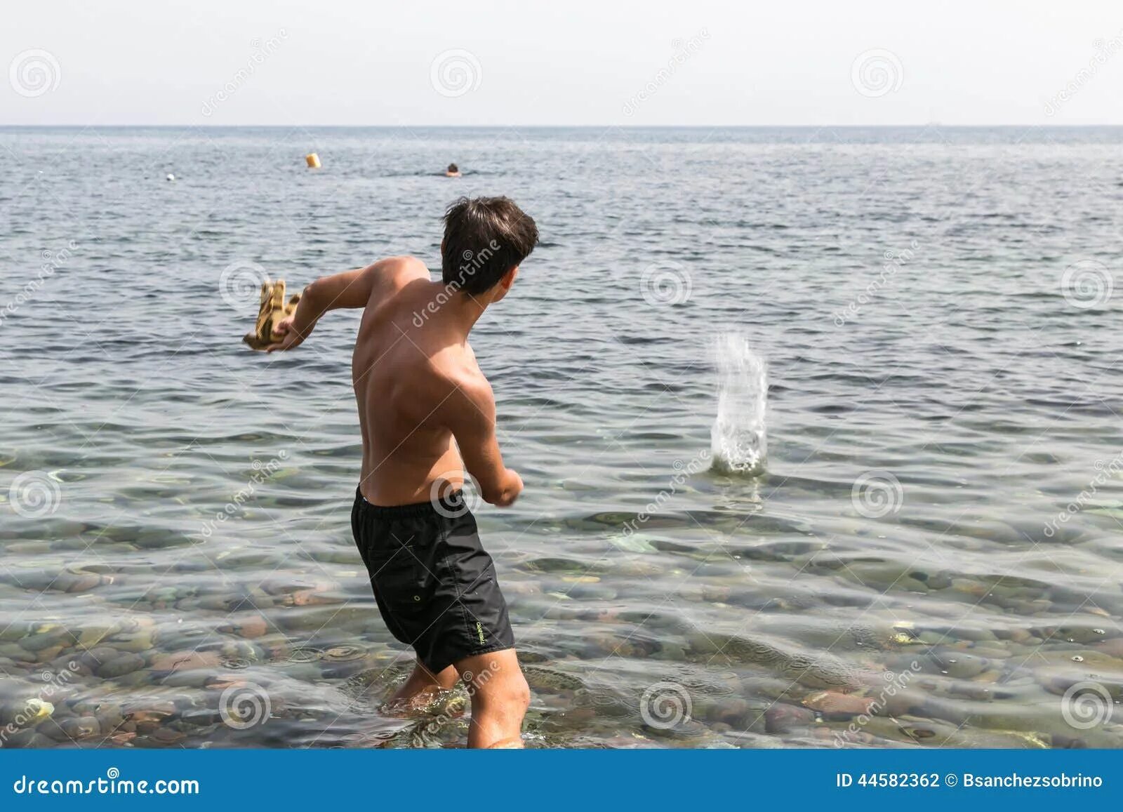 Мальчик бросает камушки в море. Кидать камни в воду. Камень брошенный в море. Мальчик кидает камень.