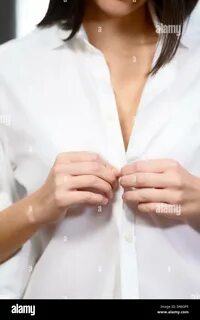 Download this stock image: Young brunette woman unbuttoning her white blous...