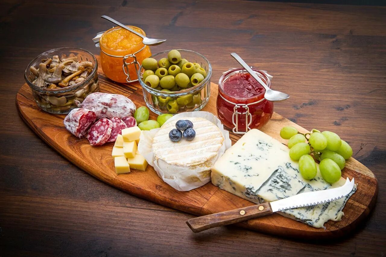 Закуски к вину. Сырная тарелка с виноградом. Сырная тарелка с оливками. Сырная тарелка на деревянной доске. Сыр на деревянной доске.
