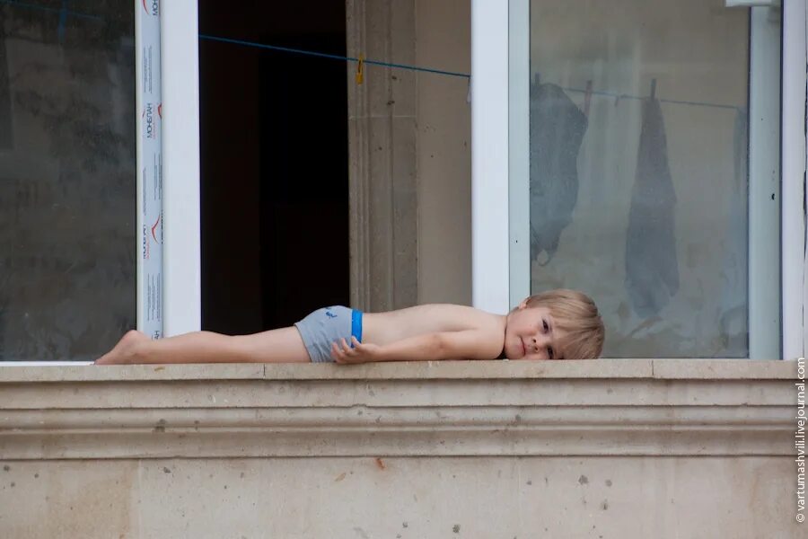 Спать на балконе. Загорает в окне. Загорает на подоконнике. Ребенок на балконе. Мальчик на балконе.