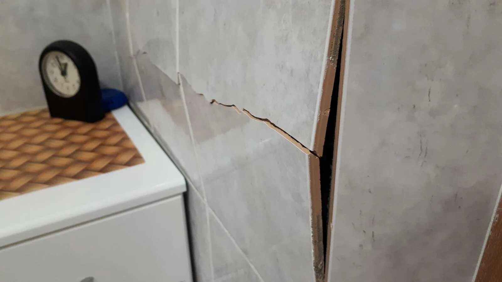 Скол керамической плитки. Плитка треснула на стене. Треснула плитка на стене в ванной. Потрескавшаяся плитка. Плитка отваливается от стены.