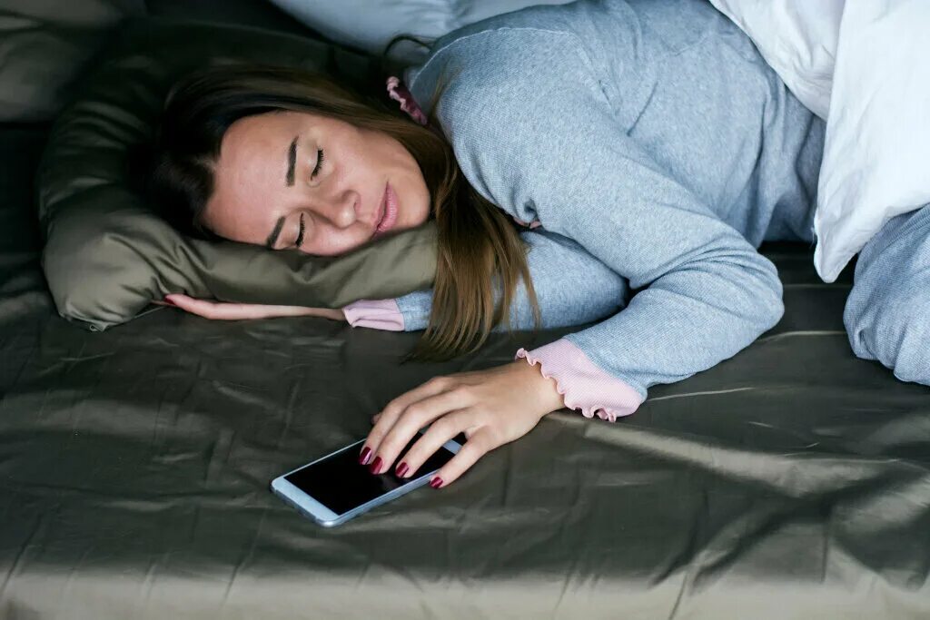 Уснул с телефоном в руках. В постели с телефоном. Женщина лежит с телефоном.