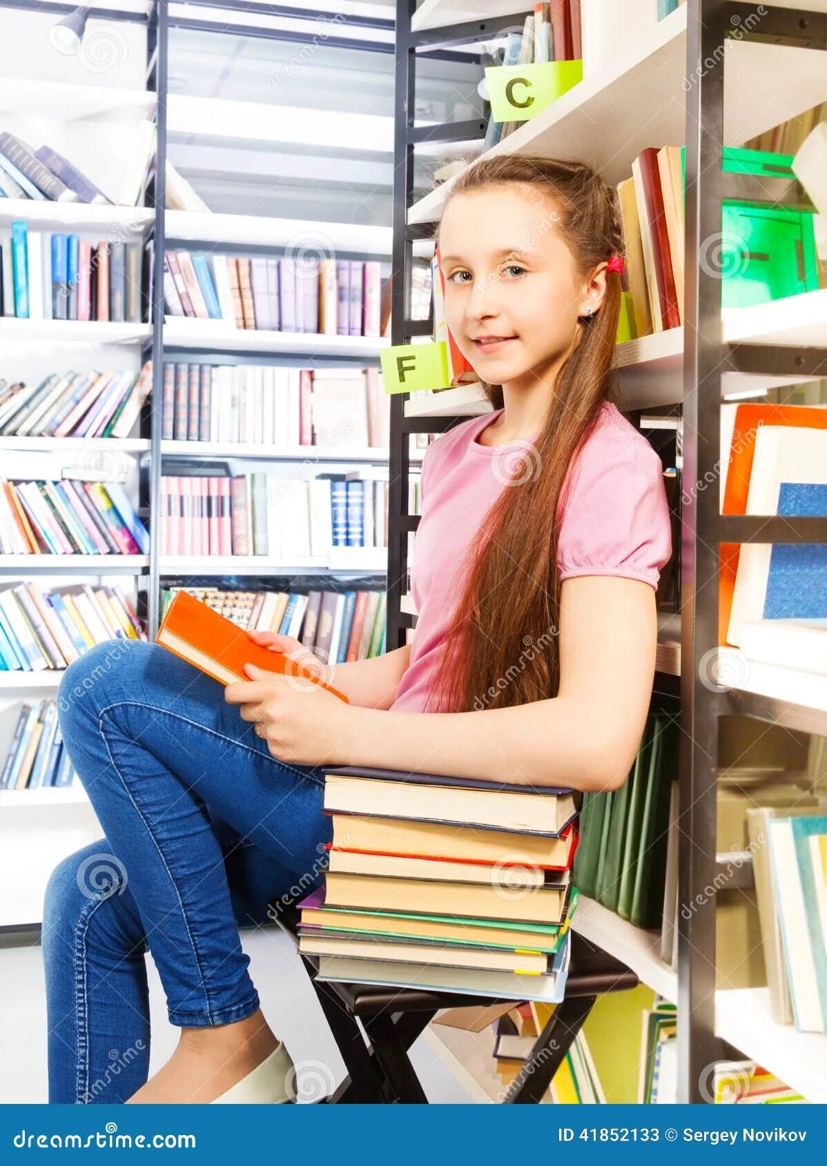 Она сидит в библиотеке. Сидит в библиотеке. Девочка сидит в библиотеке. Сидит задумчиво в библиотеке. Девочка на лесенке в библиотеке.