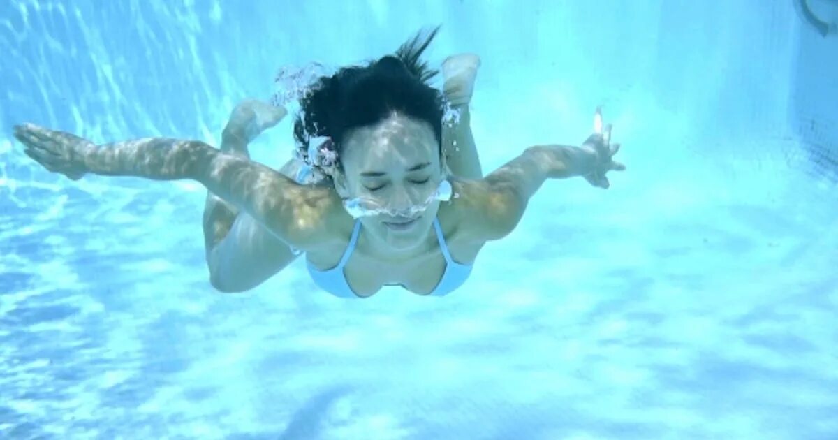 Девушка плавает в бассейне. Женщина под водой в бассейне.