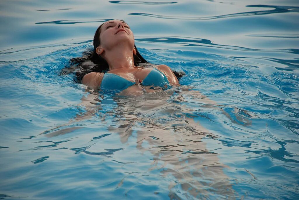 Лежать на дне бассейна. Девушка плывет на спине. Девушка плывет. Девушка плавает. Девушка плавает в море.