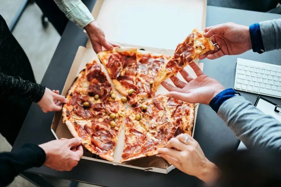 laughing friends eating pizza and having fun. They are enjoying eating and drink