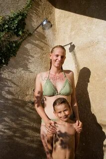 Mother and child in the bath Photo. woman in a bikini standing next to a ch...