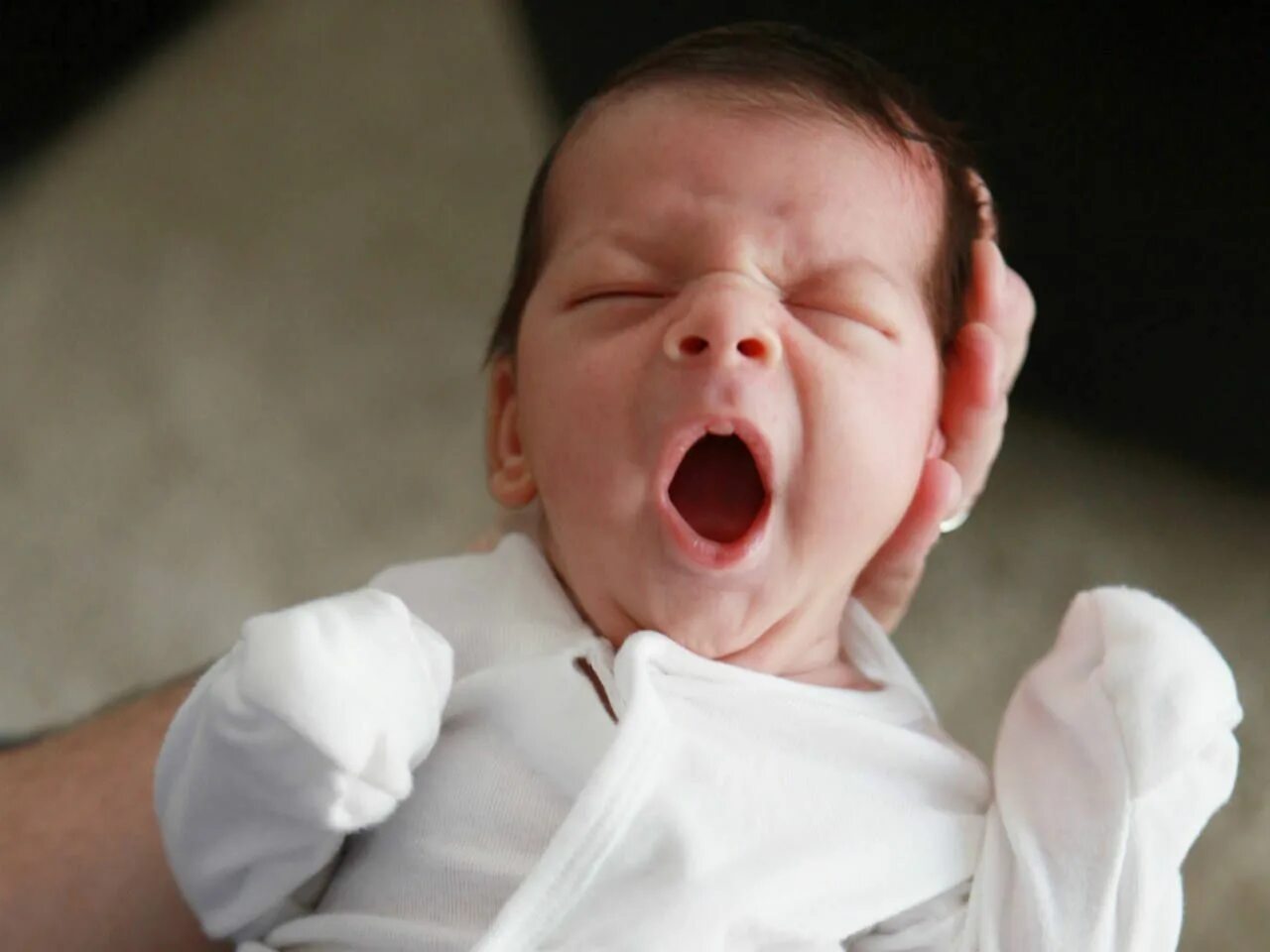 Младенец с открытым ртом. Новорожденный ребенок с открытым ртом. Беспокойный малыш. Ребенок беспокоен.