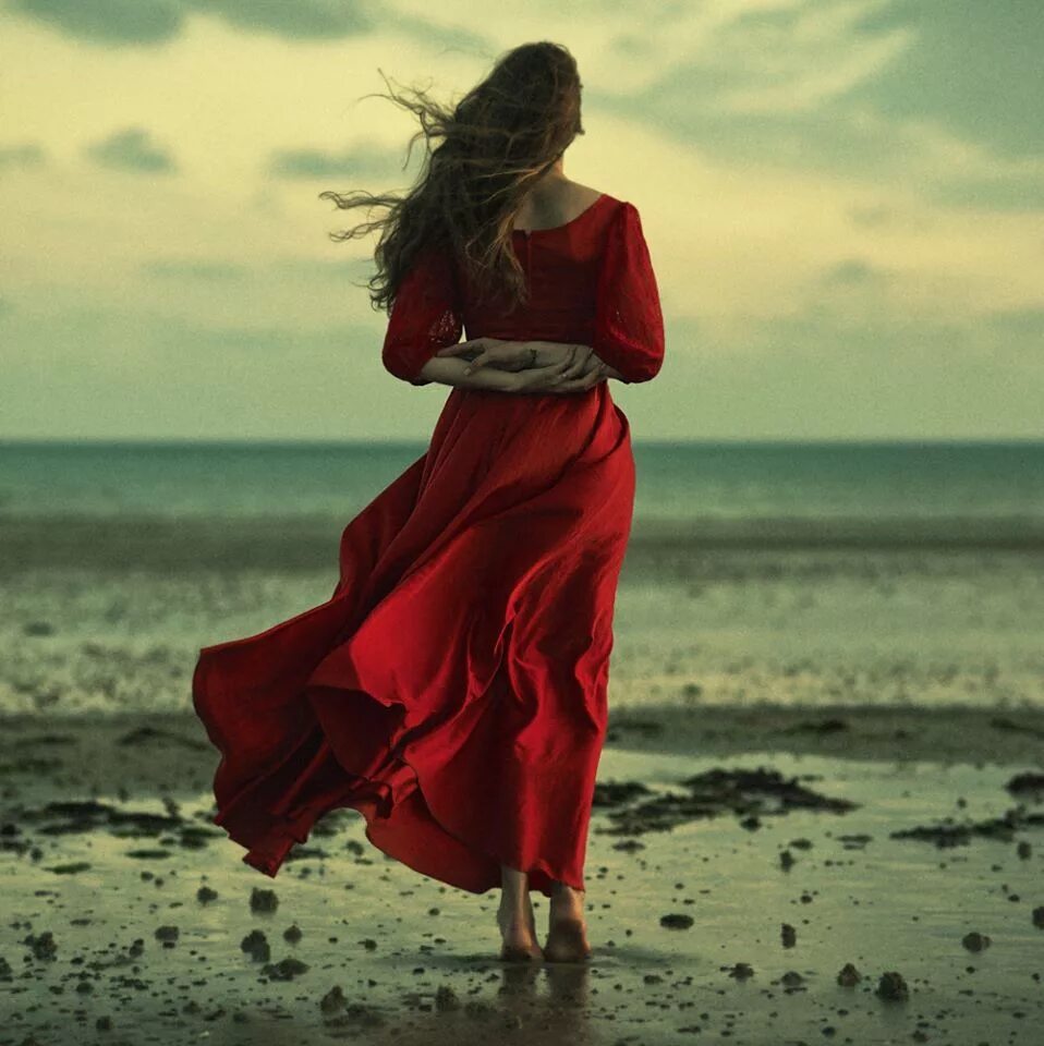 Девушка в длинном платье. Девушка в Красном платье на море. Девушка в платье на ветру. Платье развивается на ветру. Женщина идет по берегу