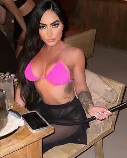 Angelina Pivarnick sitting down in a pink bikini top and black bottoms. ang...