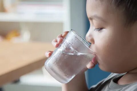A small child drinking a glass of water in Oak Lawn. 