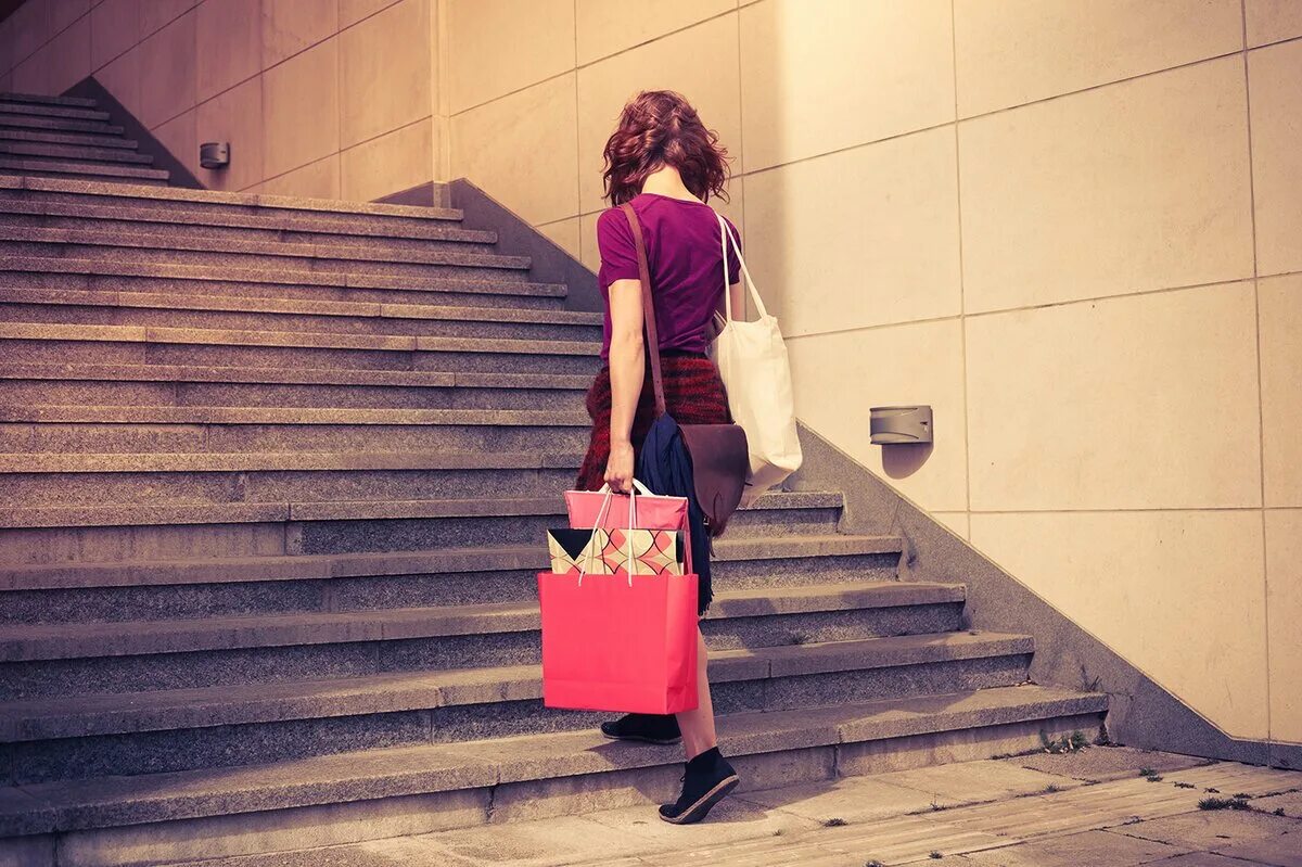 Девушка поднимается по лестнице. Человек с сумкой. Женщина с сумкой. Девушка с тяжелыми сумками. Женщина поднимается по лестнице.