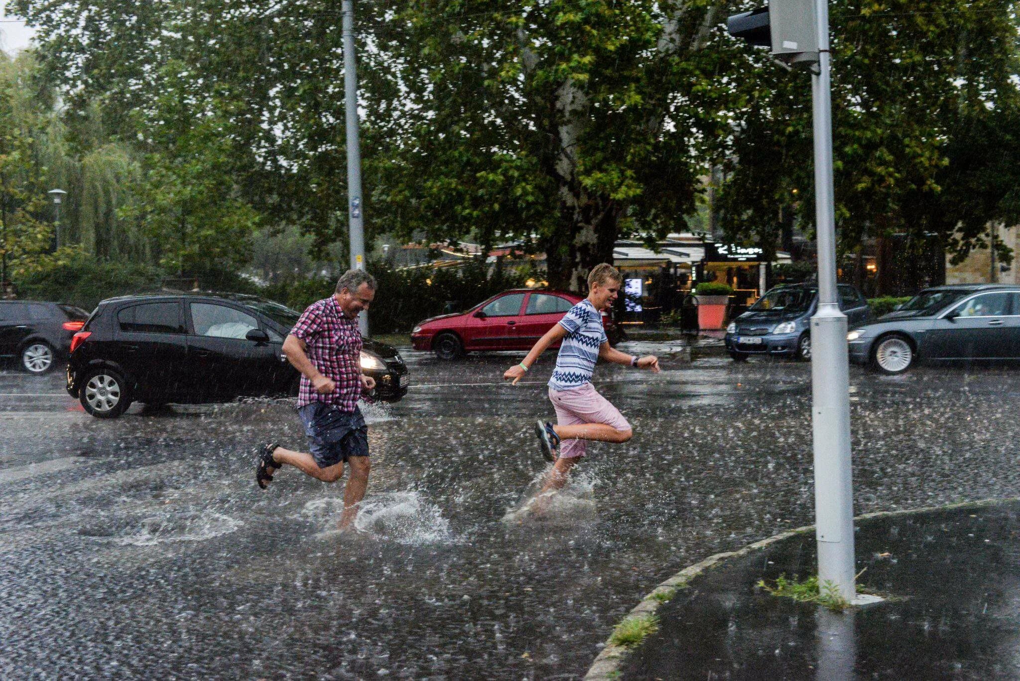 Игры в дождливую погоду. Ветер спасает от жары на улице. Тура (Венгрия) дождливый. Люди спасаются от ветра и дождя.