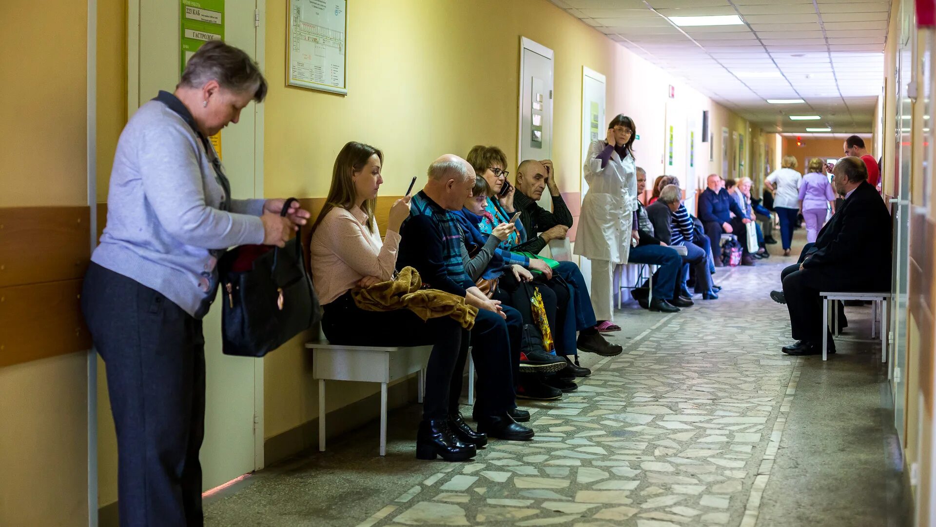 Очередь к терапевту. Очереди к терапевту. Люди в очереди в больнице. Очередь в кабинет врача. Старики в поликлинике.