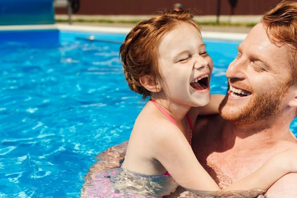 Отец смех. Дочка в бассейне. Папа с дочкой в бассейне. Счастливая семья в бассейне. Отец балуется с дочкой в бассейне.