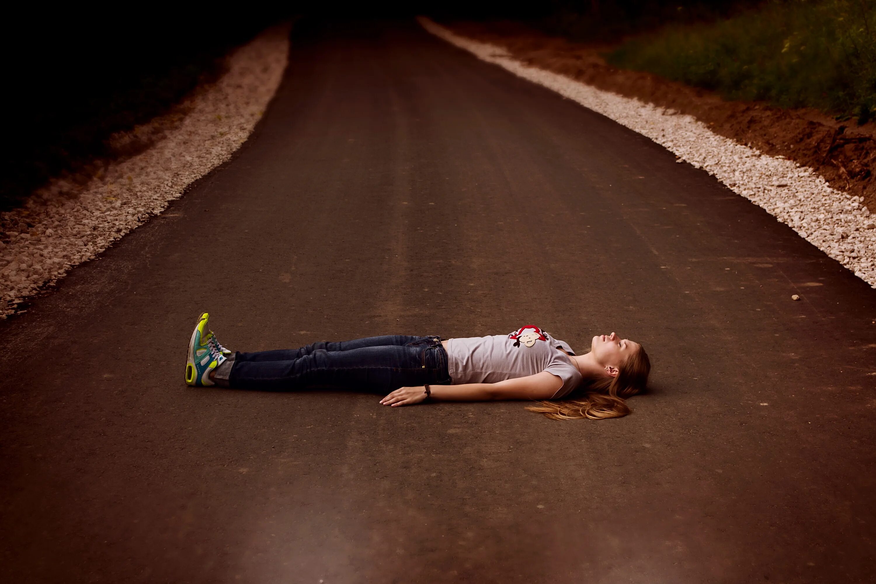 Девушка лежит на дороге.