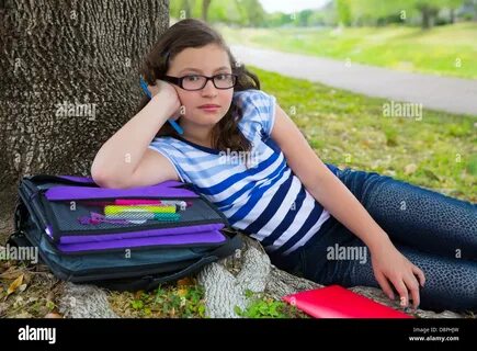Clever student teenager girl with school bag resting relaxed under park tre...