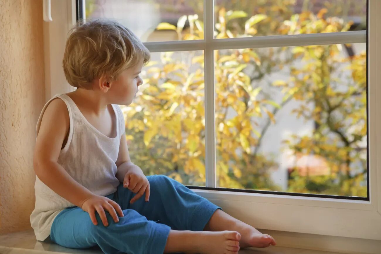 Включи свет мальчик. Ребенок на подоконнике. Мальчик на подоконнике. Мальчик сидит на подоконнике. Ребенок смотрит в окно.