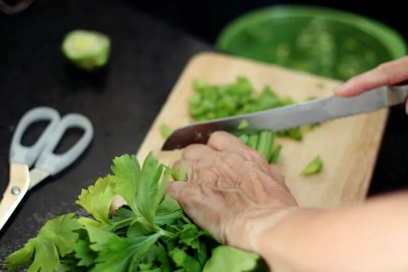 The woman is chopping the celery. A bunch of couples Camping out chopping Wood.