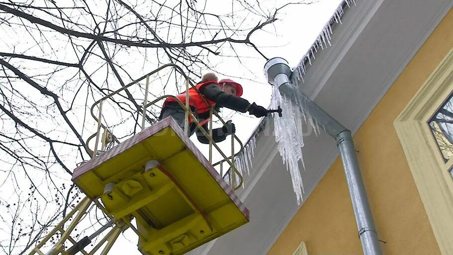 Очищены от снега и наледи. Уборка сосулек с крыш. сбивание сосулек с крыш. сбивают сосульки с крыш. очистка кровли от снега и наледи.