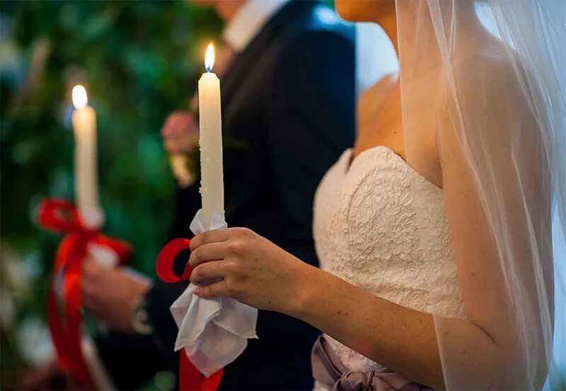 Венчальные свечи. Венчальные свечи в церкви. Свадьба. Венчальные свечи в руках.