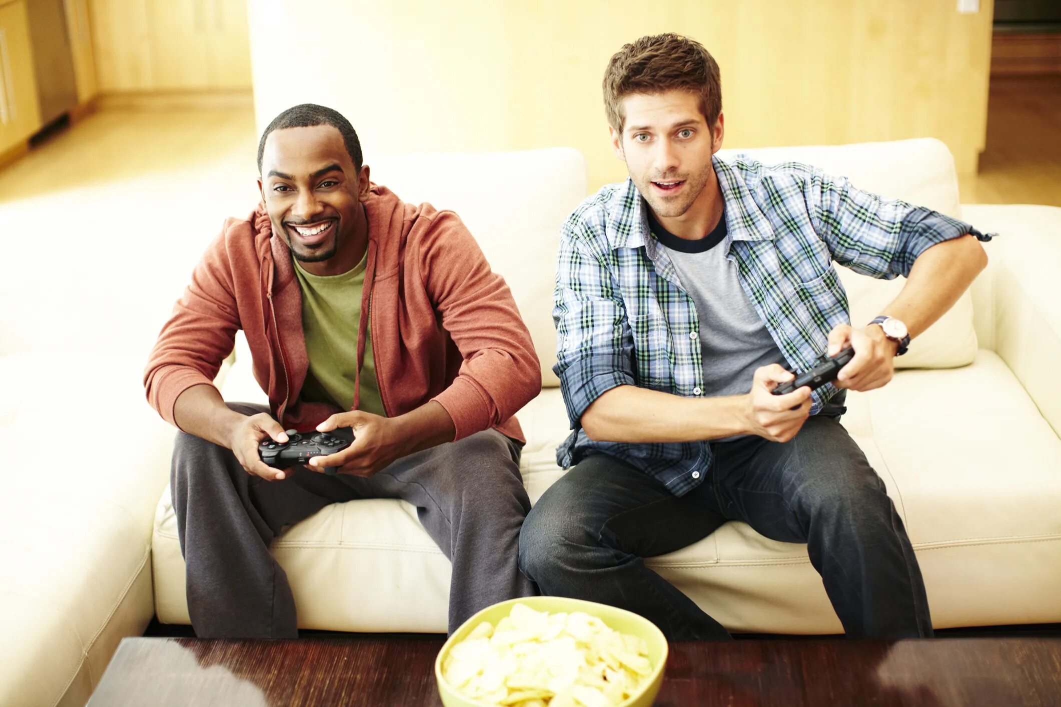 Playing fool. TV man. Man playing PLAYSTATION. Playing man sitting. Two mans sitting.