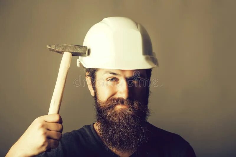 Бьют по каске. Бородатый в каске. мужик в каске с молотком. каска и молоток. бородатый мужик в каске.