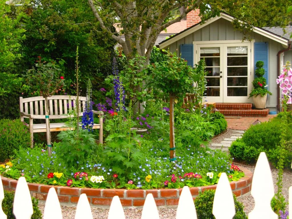 Украшение садового участка. Красивая дача. Цветы в палисаднике перед домом. Украшение цветами дачного участка.