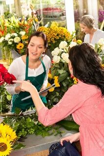Young florist ordering roses woman customer flower market retail shop - 176...